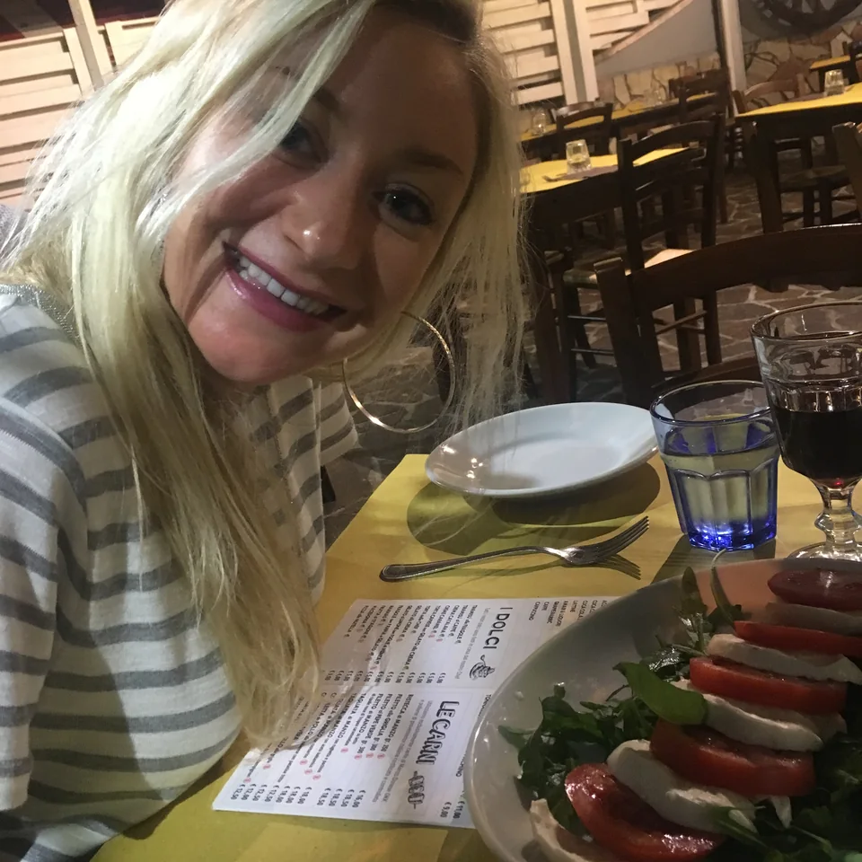 Kristin smiling beside a plate of tomatoes and mozzarella